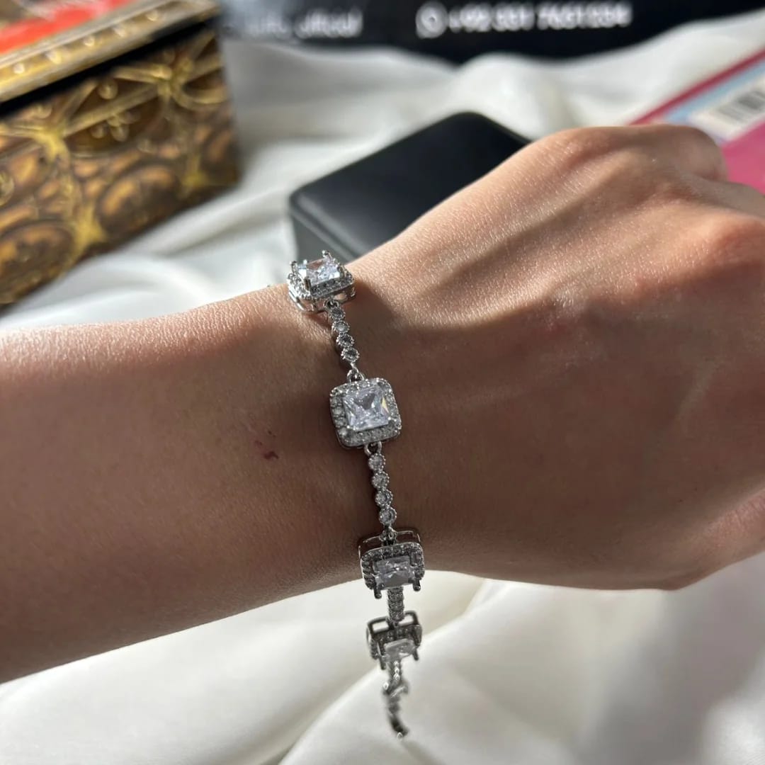 Silver bracelet with square-shaped crystals on a wrist, with a blurred background