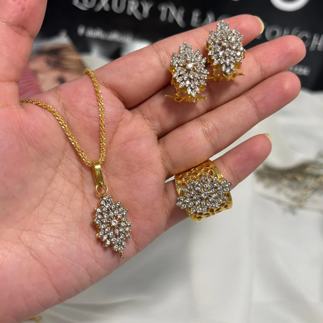 Gold jewelry set with necklace, earrings, and ring held in a hand.