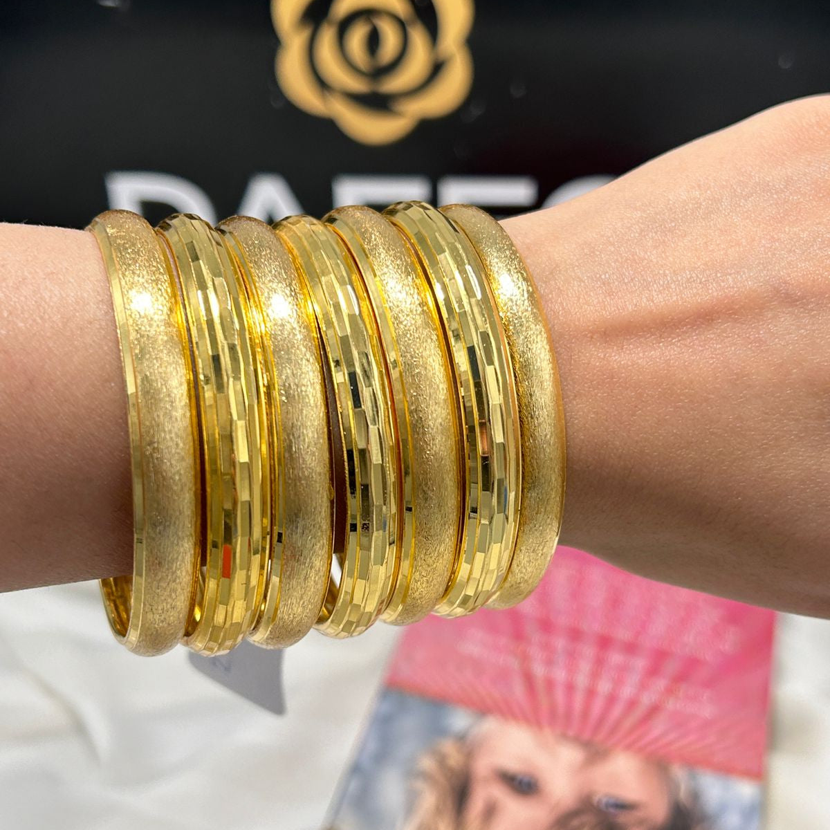 Gold bangles on a wrist with a blurred background