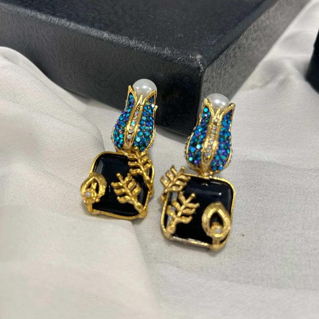 Pair of earrings with gold, blue, and black design on a white surface.
