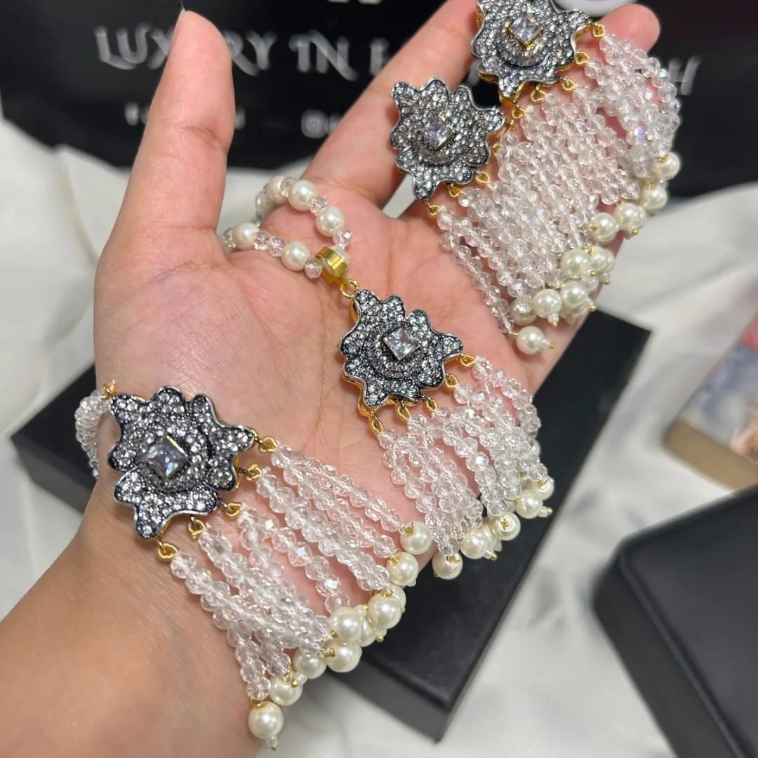 Hand wearing a pearl bracelet with decorative elements on a blurred background