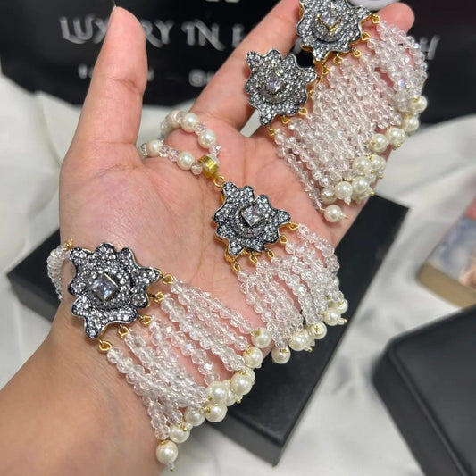 Hand wearing a pearl bracelet with decorative elements on a blurred background