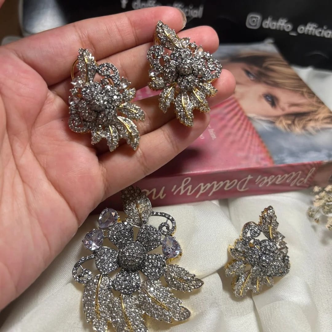 Decorative earrings held in a hand with a blurred background 3D Floral Zirconic Set