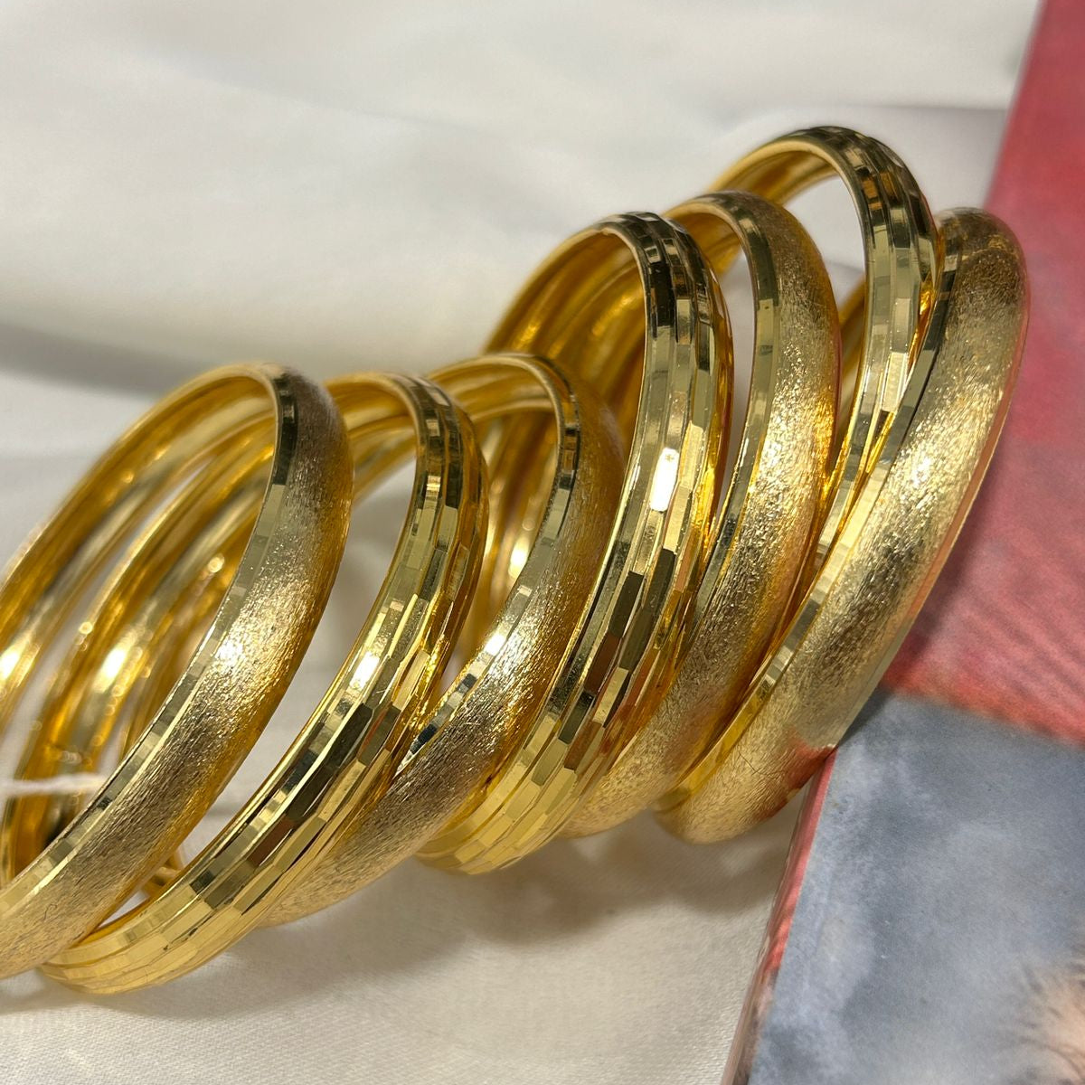 Set of gold bangles on a white surface with a blurred background