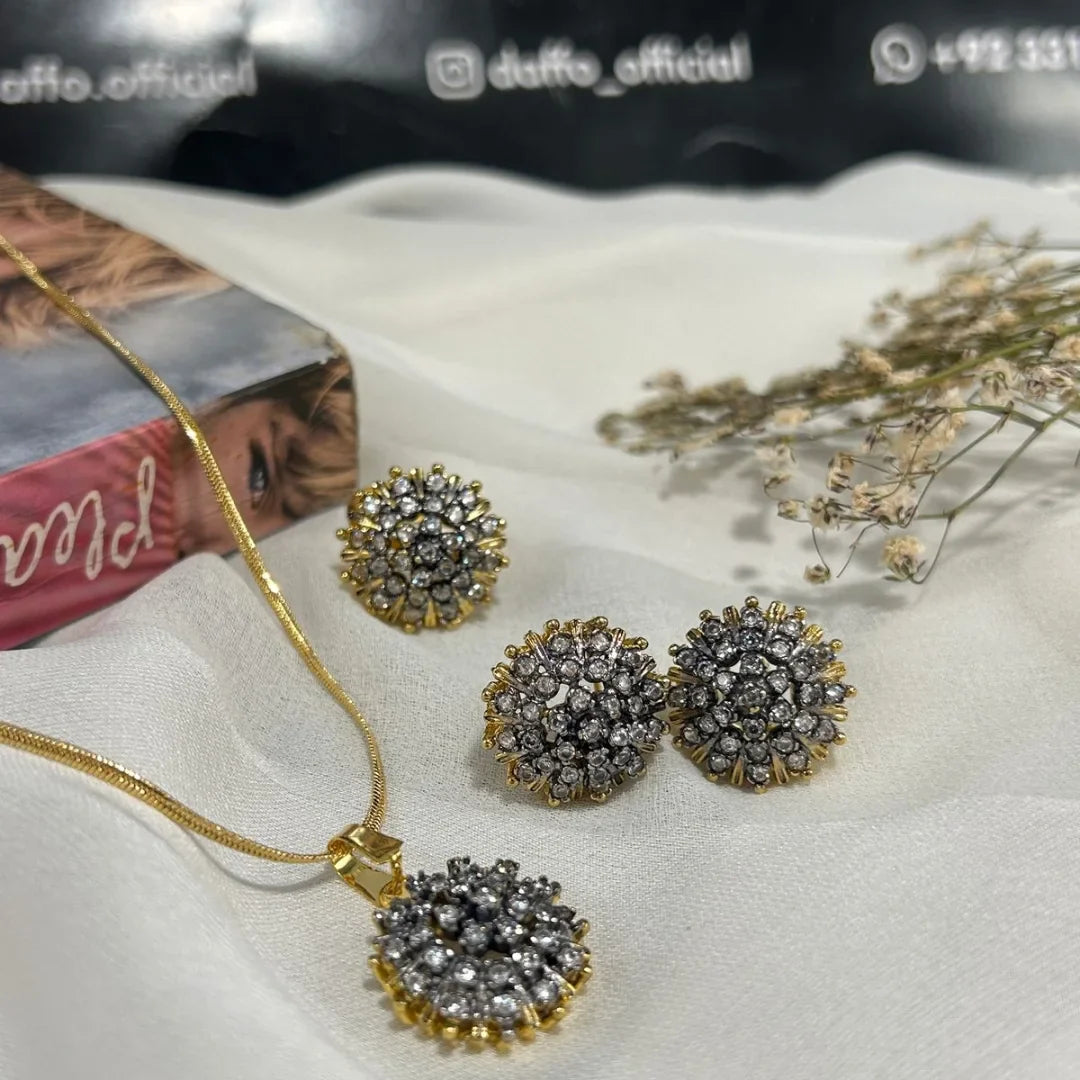 Gold necklace and earrings with gemstones on a white surface. GOLDPLATED DIAMOND LOOK COMBO SET 